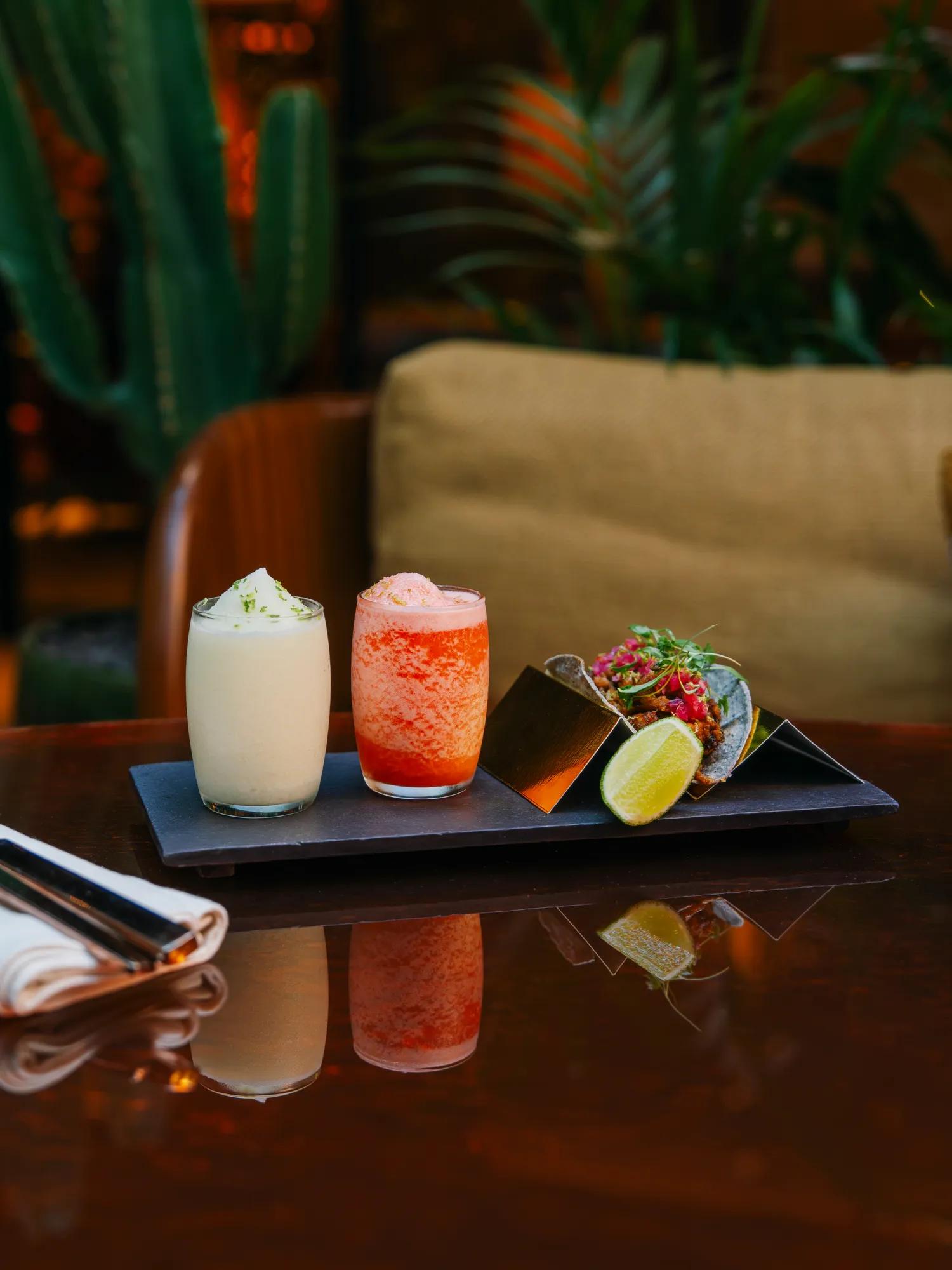 Two frozen cocktails and a taco sitting on a table