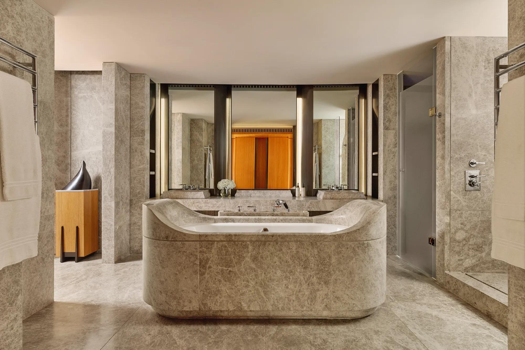 Luxurious marble bathroom with sculptural central bathtub, dual sinks, and soft ambient lighting in the Opus Suite