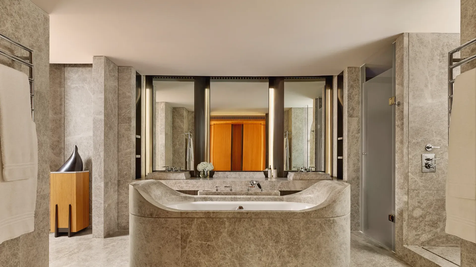 Luxurious marble bathroom with sculptural central bathtub, dual sinks, and soft ambient lighting in the Opus Suite