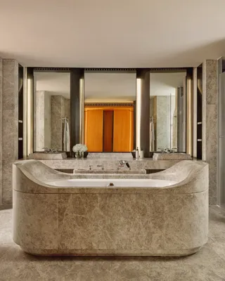 Luxurious marble bathroom with sculptural central bathtub, dual sinks, and soft ambient lighting in the Opus Suite
