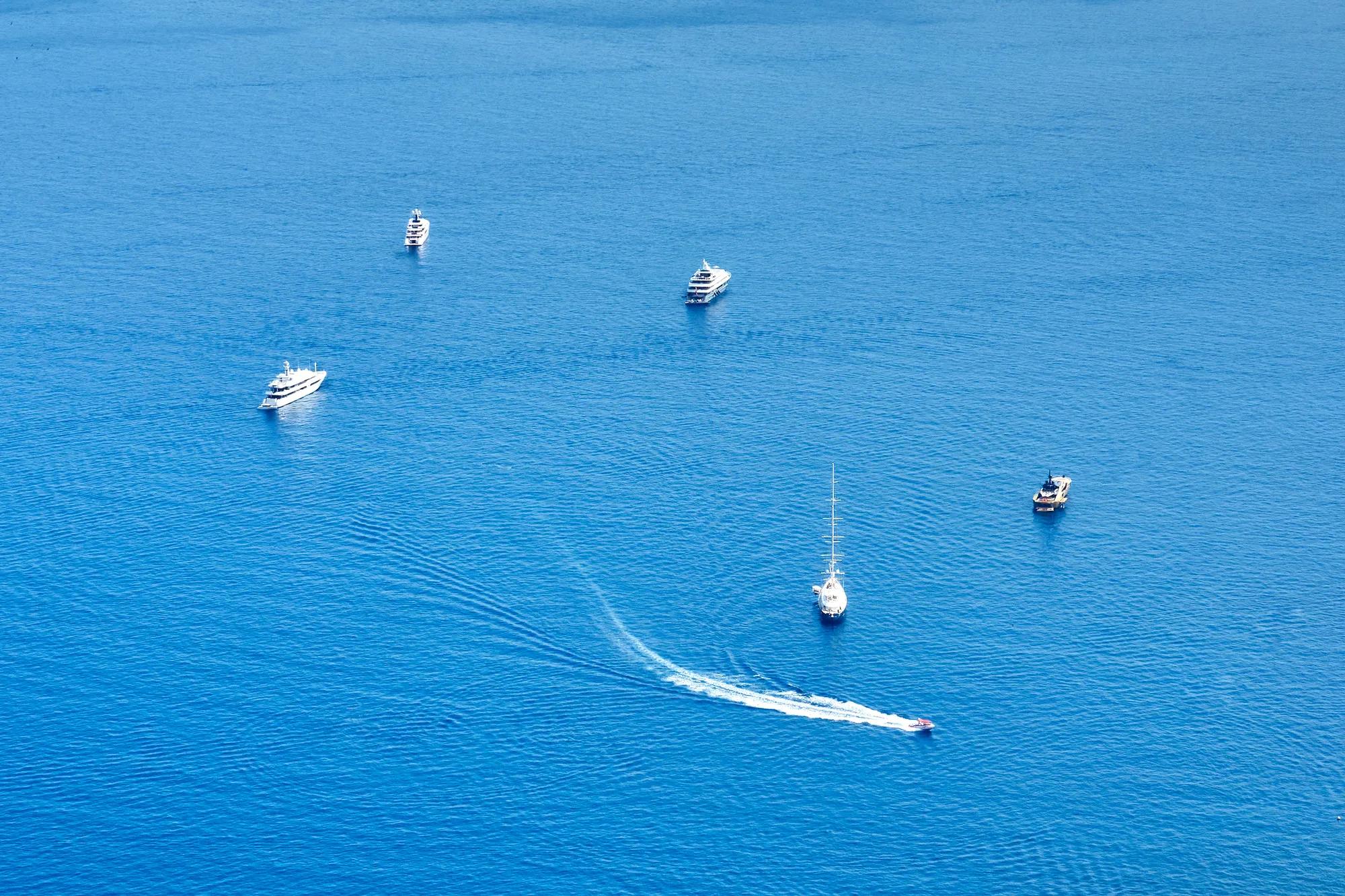 Six boats sailing in the vast blue sea