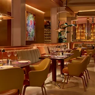 A restaurant sitting area with tables, chairs, and soft ambient lighting
