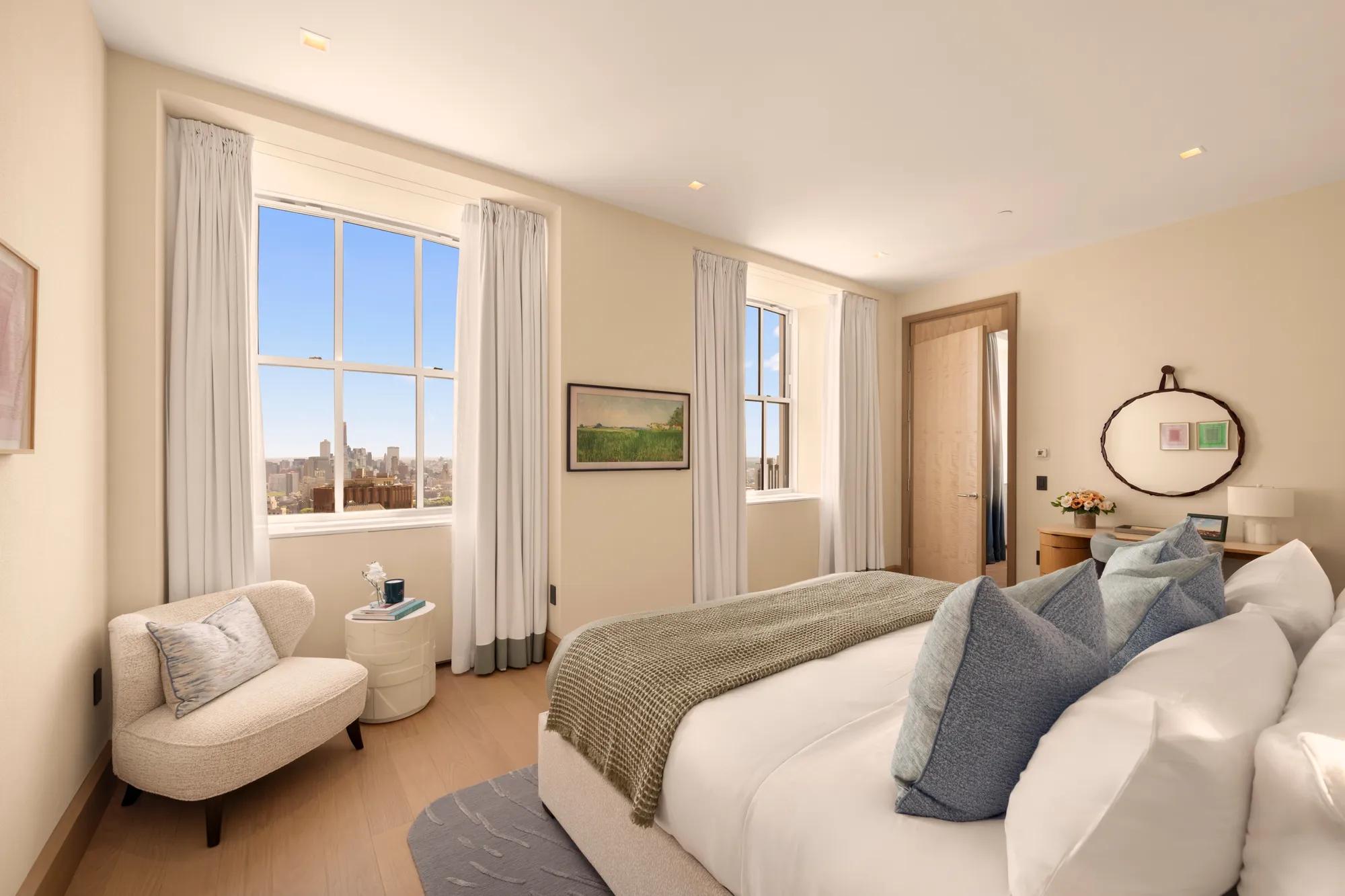 Bright, residential-style bedroom with king bed, soft neutral furnishings and expansive city skyline views through tall windows.