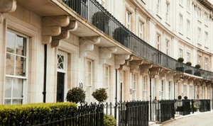 Elegant curved terrace of white stone houses with black railings, balconies, and potted greenery.