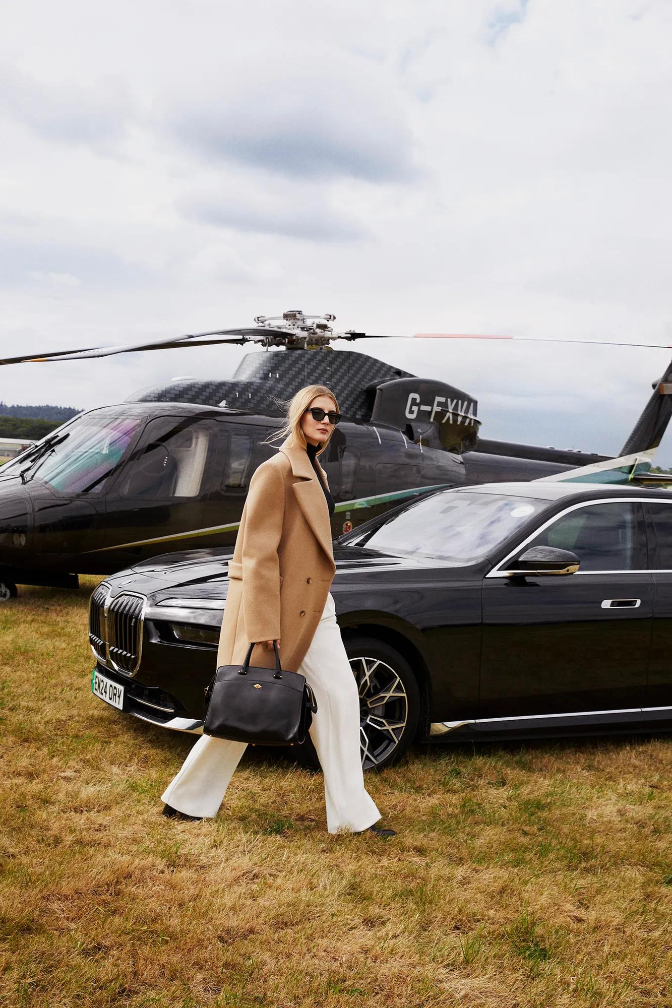 A woman passing in front of a helicopter with its rotor blades visible above