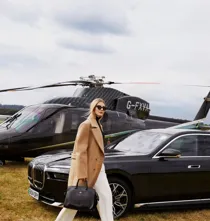 A woman passing in front of a helicopter with its rotor blades visible above
