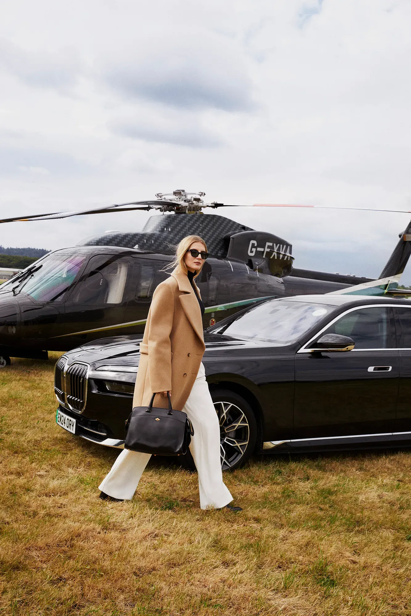 A woman passing in front of a helicopter with its rotor blades visible above