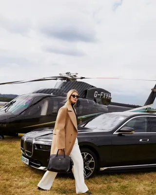 A woman passing in front of a helicopter with its rotor blades visible above