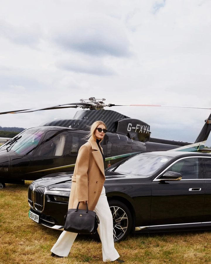 A woman passing in front of a helicopter with its rotor blades visible above