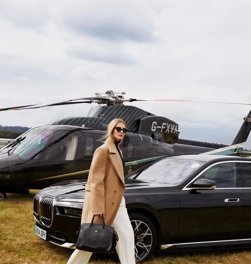 A woman passing in front of a helicopter with its rotor blades visible above