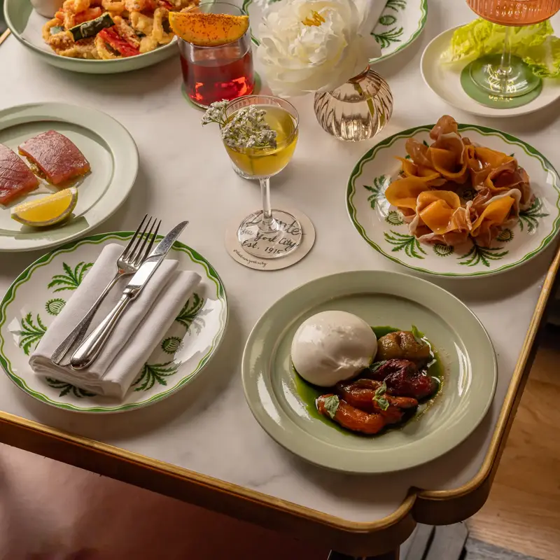 Assorted Italian dishes, cocktails, and seafood elegantly arranged on a marble restaurant table.