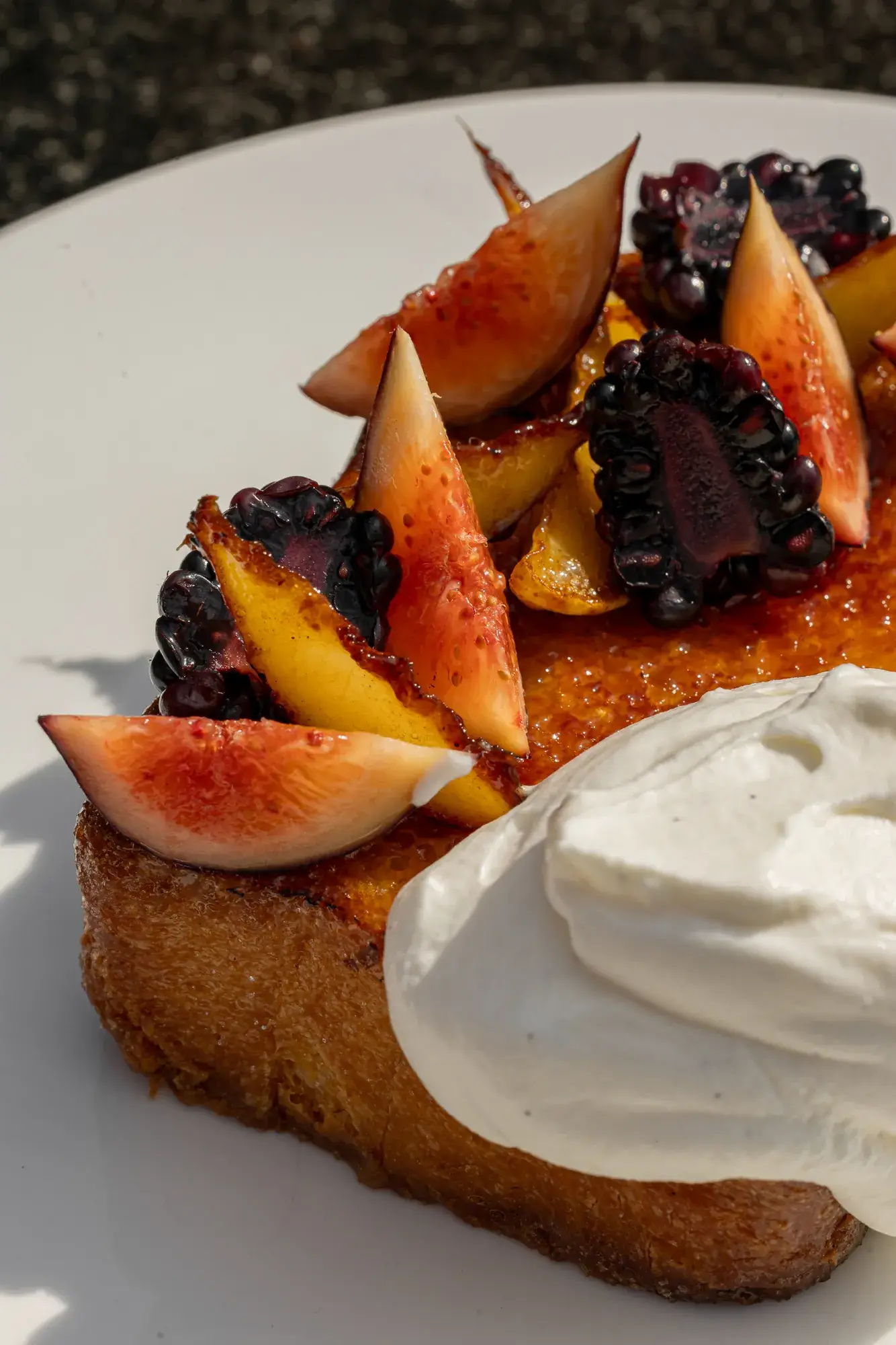 Thick brioche toast topped with fresh figs and blackberries, served with a generous dollop of whipped cream.