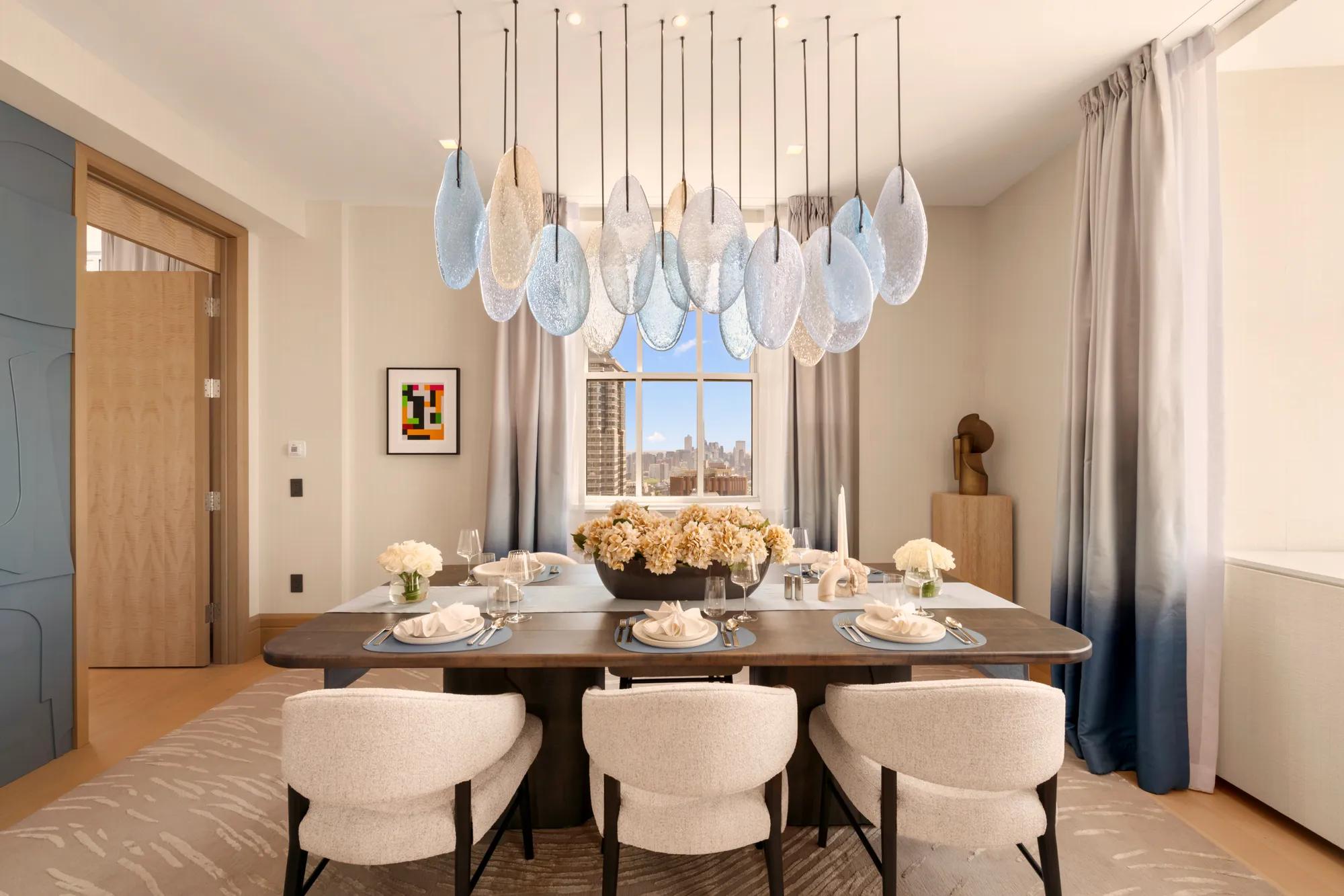 Contemporary dining room with sculptural pendant lighting, bespoke furnishings and city views framed by floor-to-ceiling windows.
