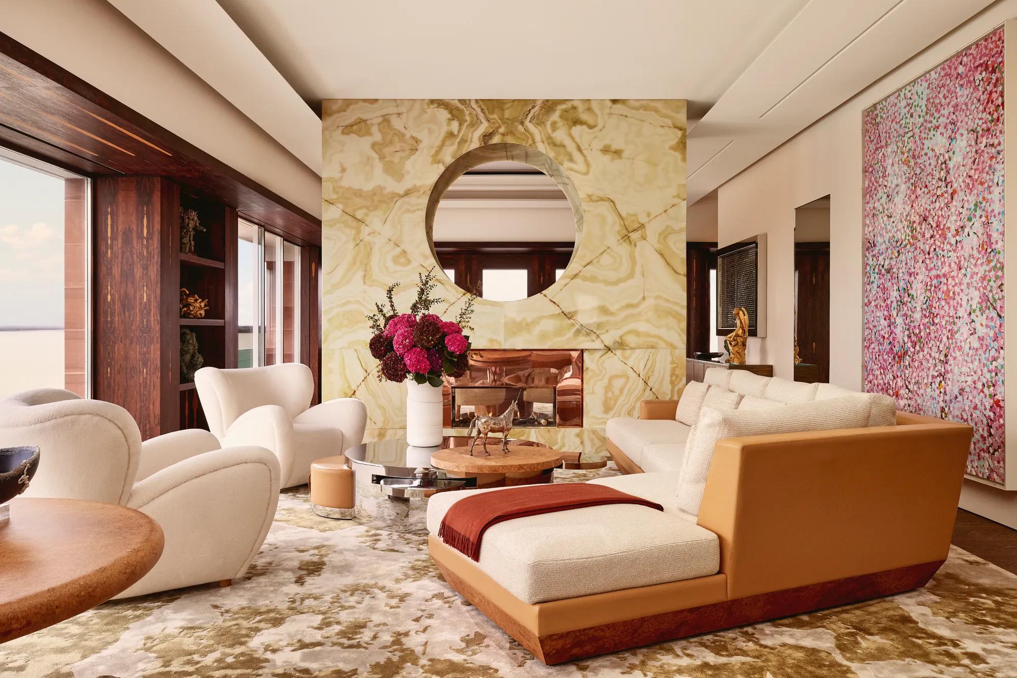 Contemporary living room at Claridge’s with a marble fireplace, cream sofas, modern artwork, and warm natural light.
