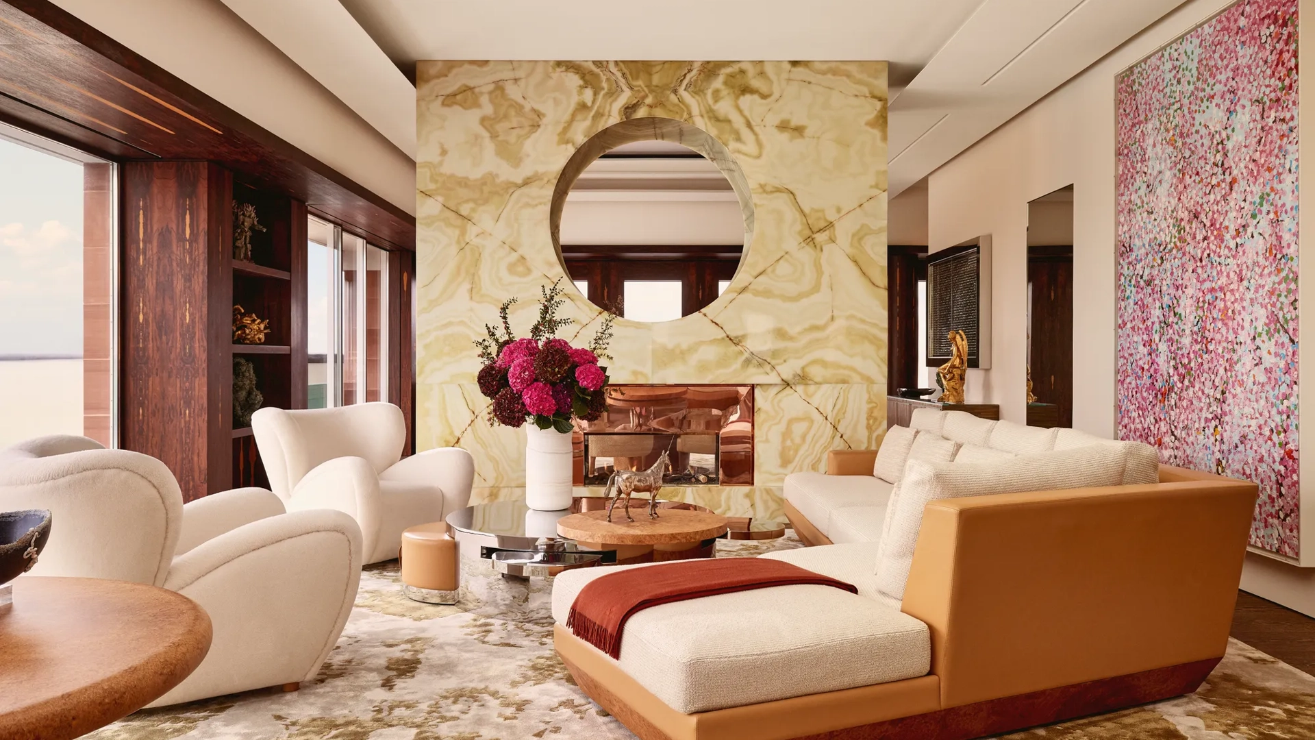 Contemporary living room at Claridge’s with a marble fireplace, cream sofas, modern artwork, and warm natural light.