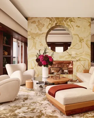 Contemporary living room at Claridge’s with a marble fireplace, cream sofas, modern artwork, and warm natural light.