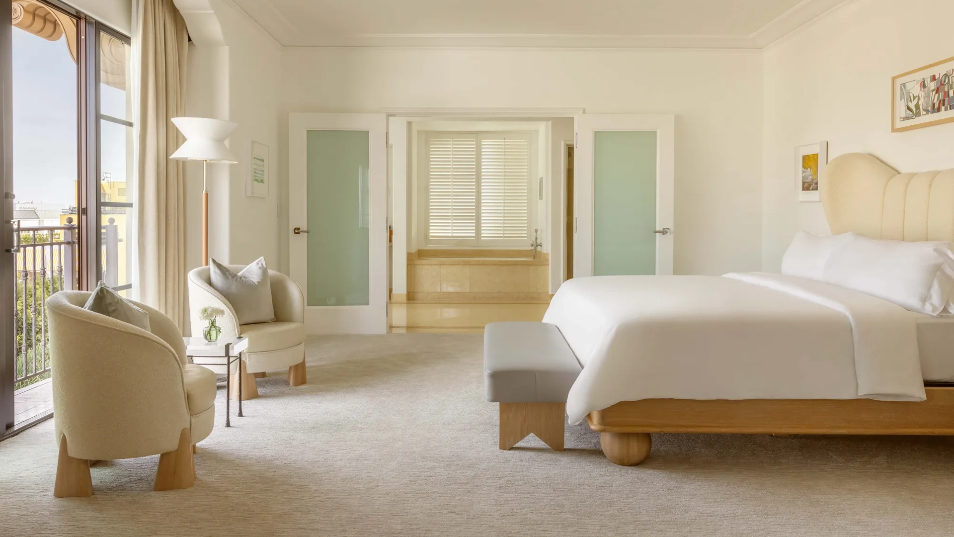 Side view of the Hollywood Suite master bedroom with french doors open into the master marble bathroom with a freestanding tub