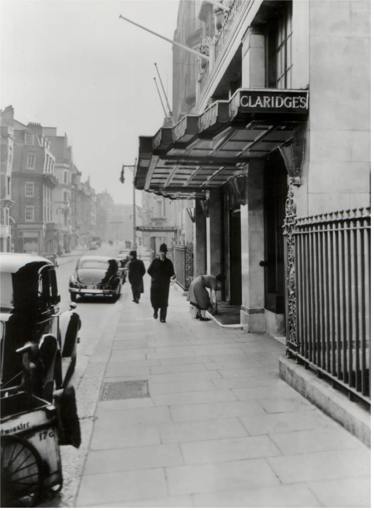 Historic black-and-white view of Claridge’s entrance with vintage cars and pedestrians on Brook Street.