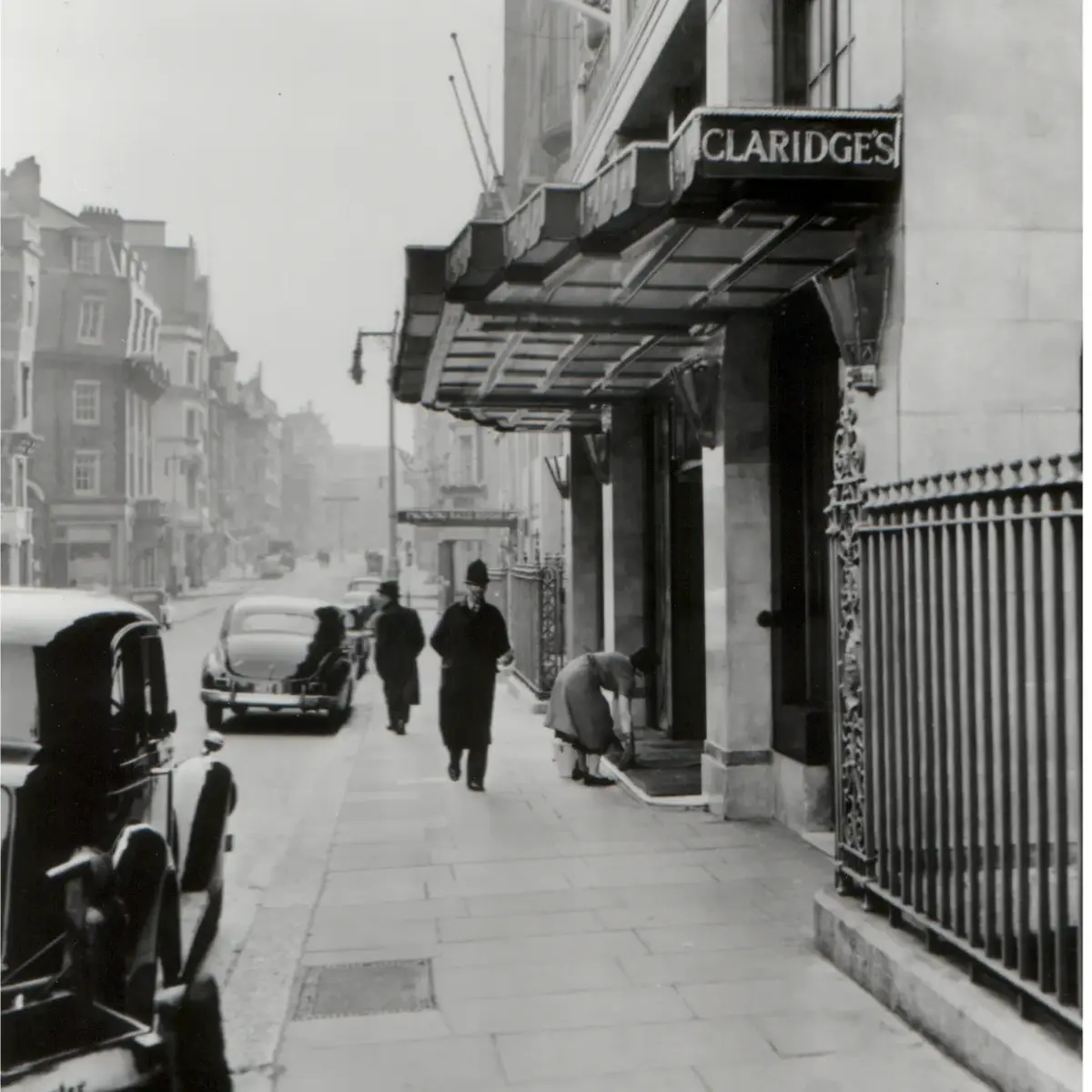 Historic black-and-white view of Claridge’s entrance with vintage cars and pedestrians on Brook Street.