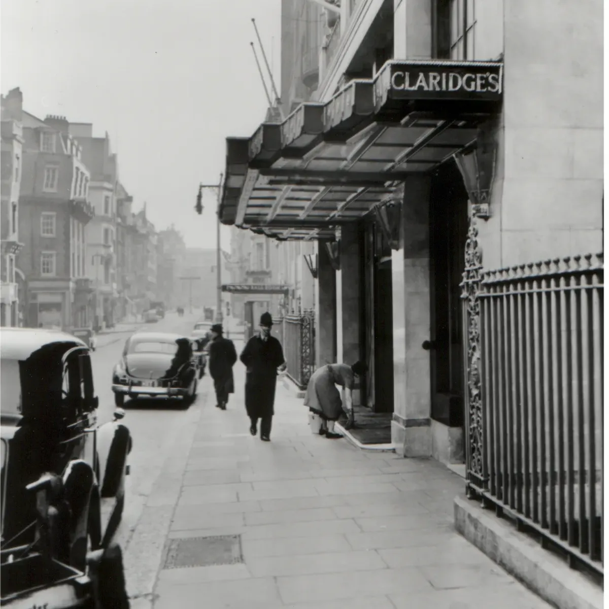 Historic black-and-white view of Claridge’s entrance with vintage cars and pedestrians on Brook Street.