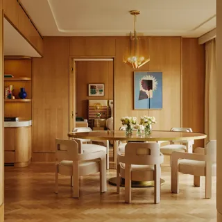 Dining table set for six with floral centrepieces, natural wood finishes and park views through a floor-to-ceiling window.