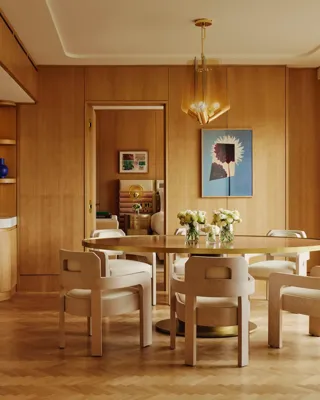 Dining table set for six with floral centrepieces, natural wood finishes and park views through a floor-to-ceiling window.
