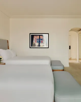 Two-queen bedroom with balcony access, featuring contemporary décor and seating area.