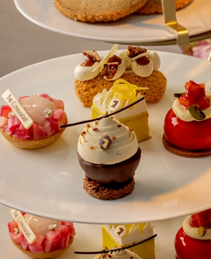 Selection of colorful mini pastries and cakes arranged on a tiered white plate stand.