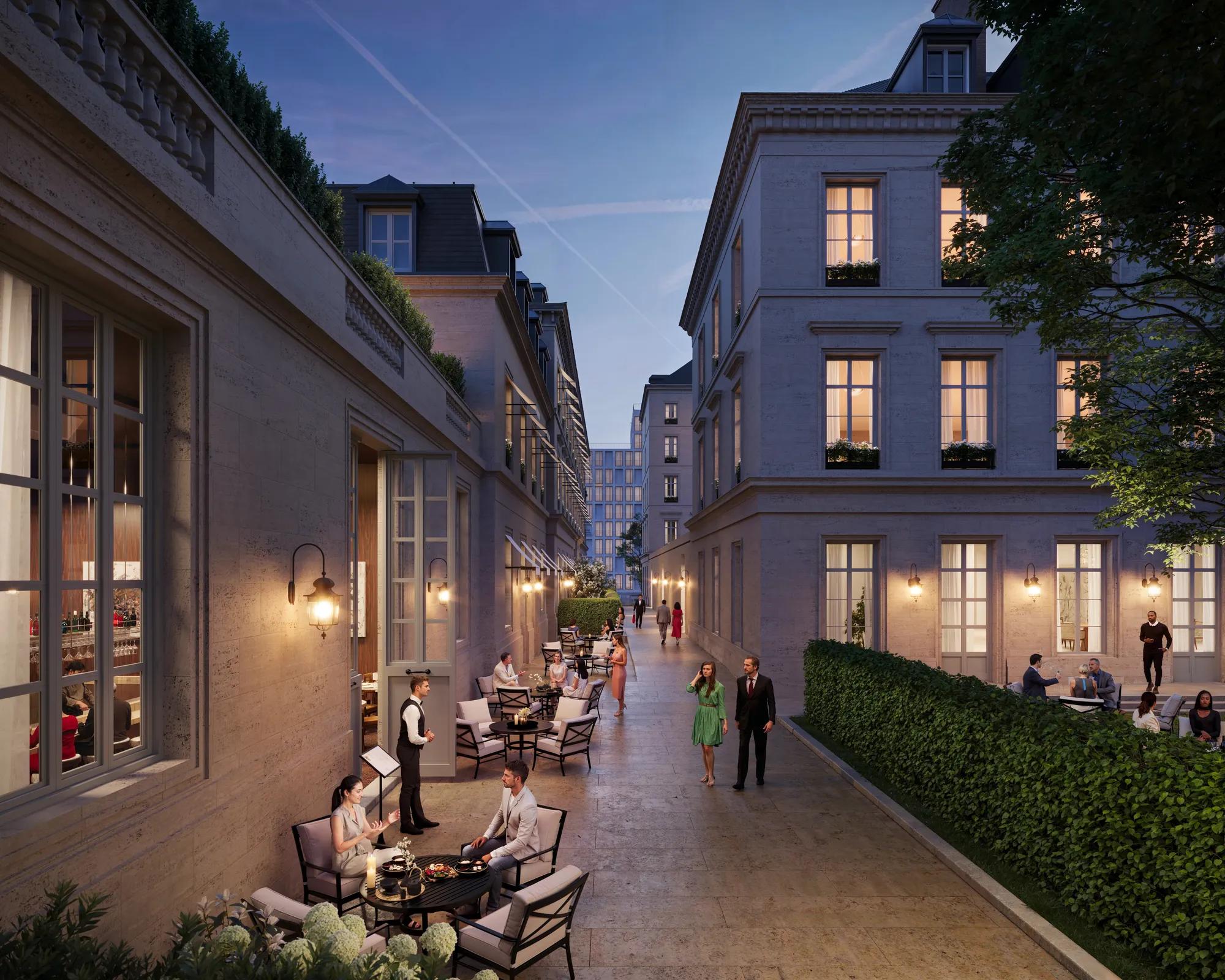 Evening courtyard with outdoor dining, guests seated at tables, warm lighting, and elegant stone buildings lining a narrow walkway.