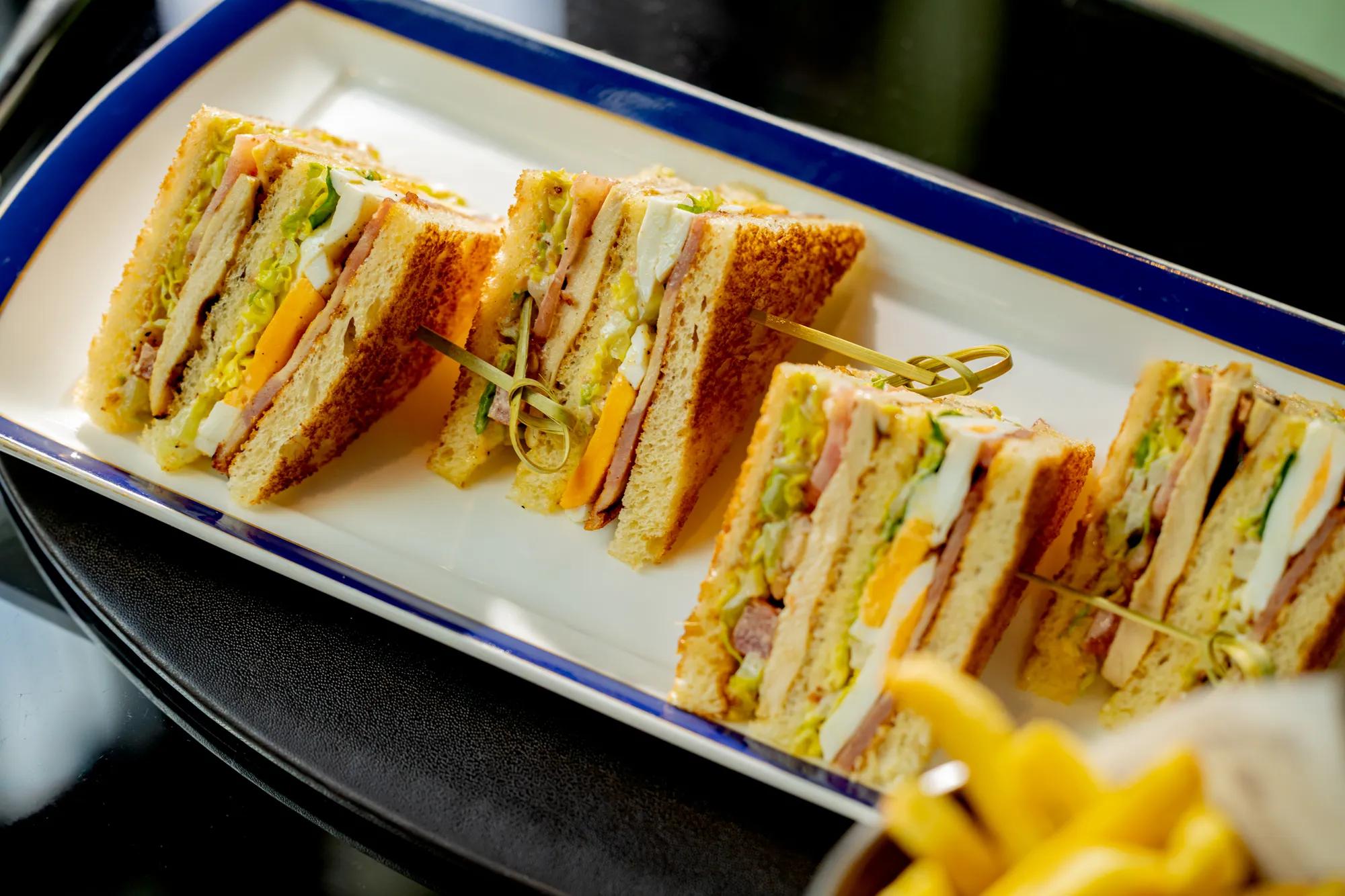 Club sandwiches cut into portions and served on a rectangular platter.