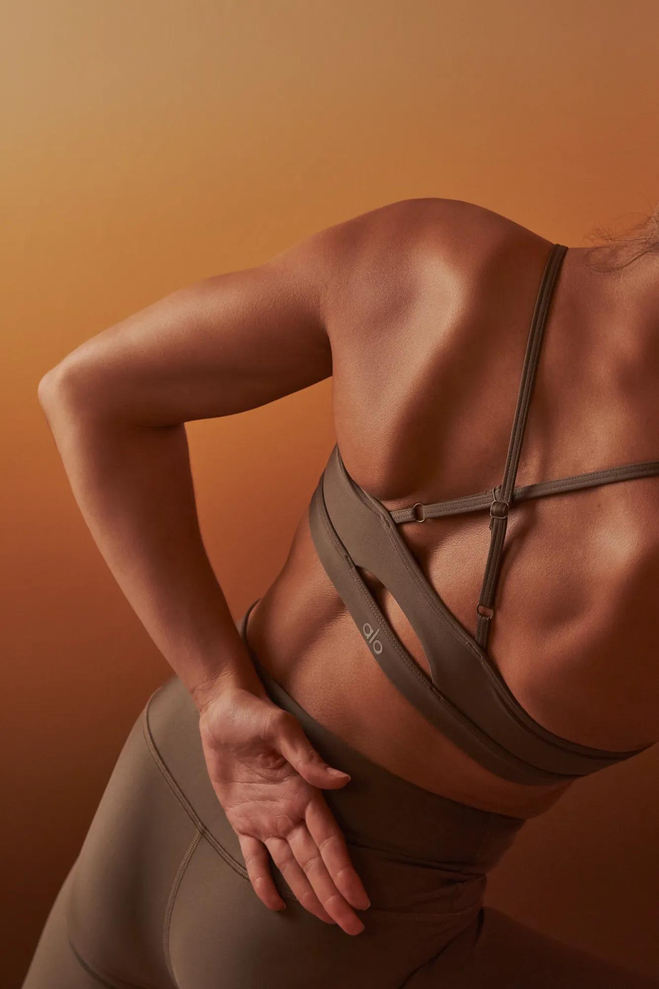 Person stretching their lower back in activewear against a warm-toned studio backdrop.