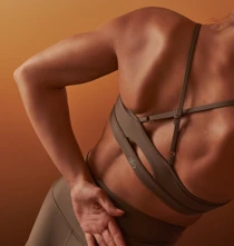 Person stretching their lower back in activewear against a warm-toned studio backdrop.