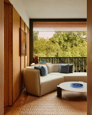 A modern hotel room living area with a beige sofa, coffee table, and soft ambient lighting.