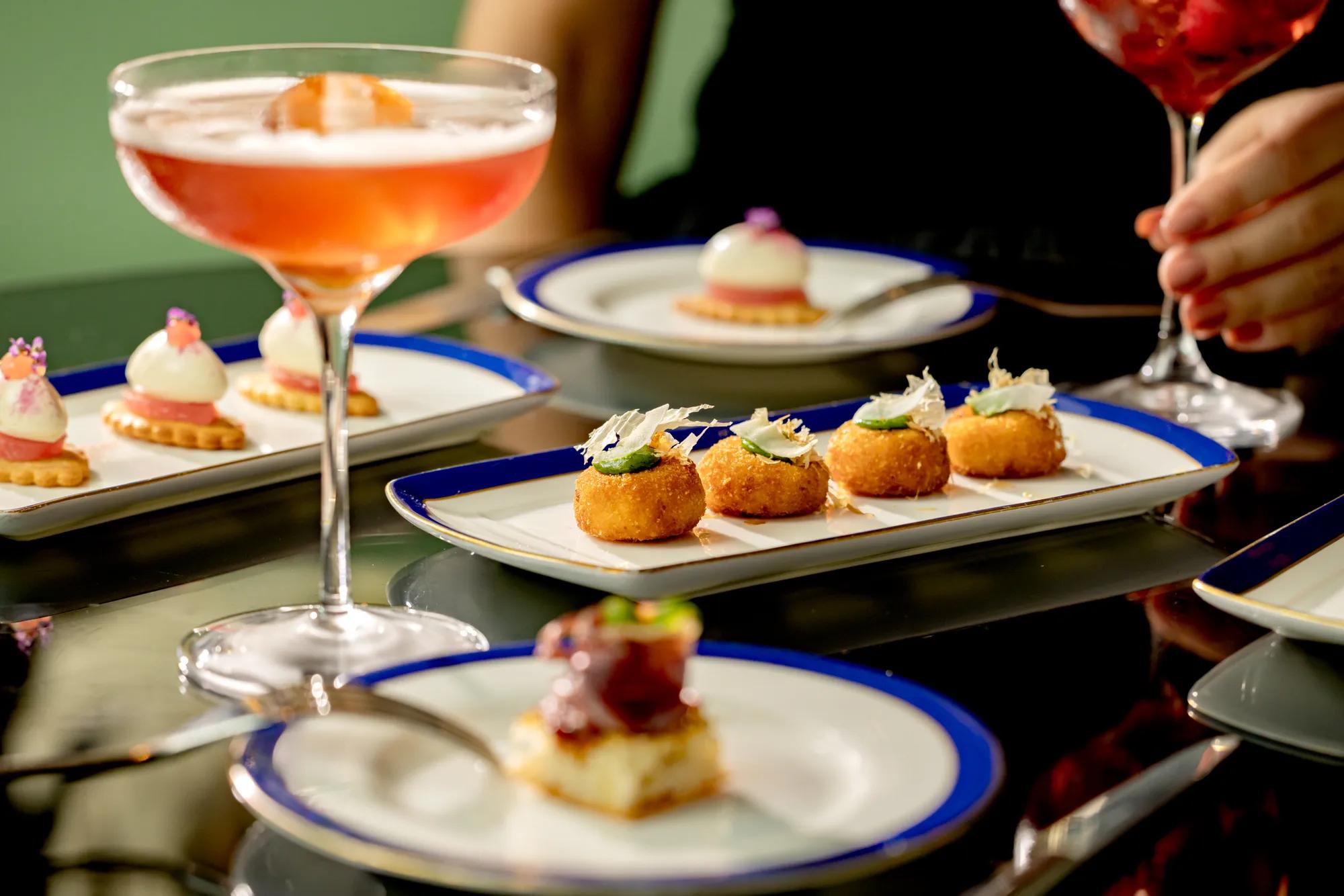 Cocktails and small plates served on a table, including canapés and desserts.