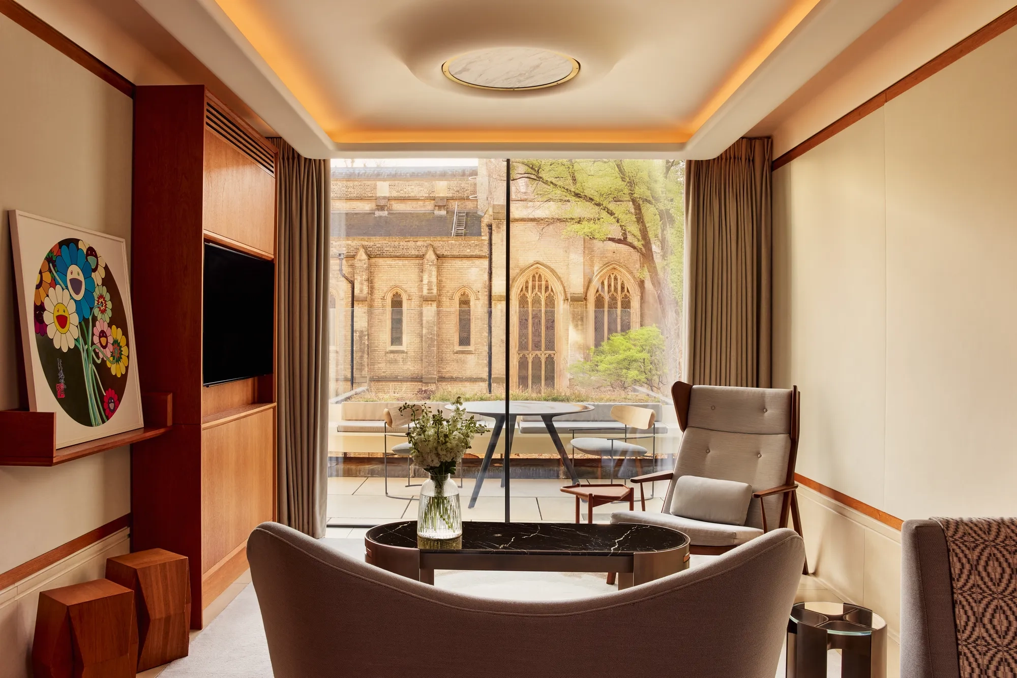 Modern living area with armchairs, artwork, and terrace view of historic church windows.