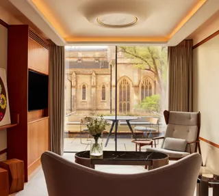 Modern living area with armchairs, artwork, and terrace view of historic church windows.
