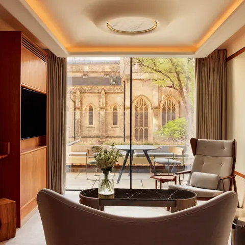 Modern living area with armchairs, artwork, and terrace view of historic church windows.