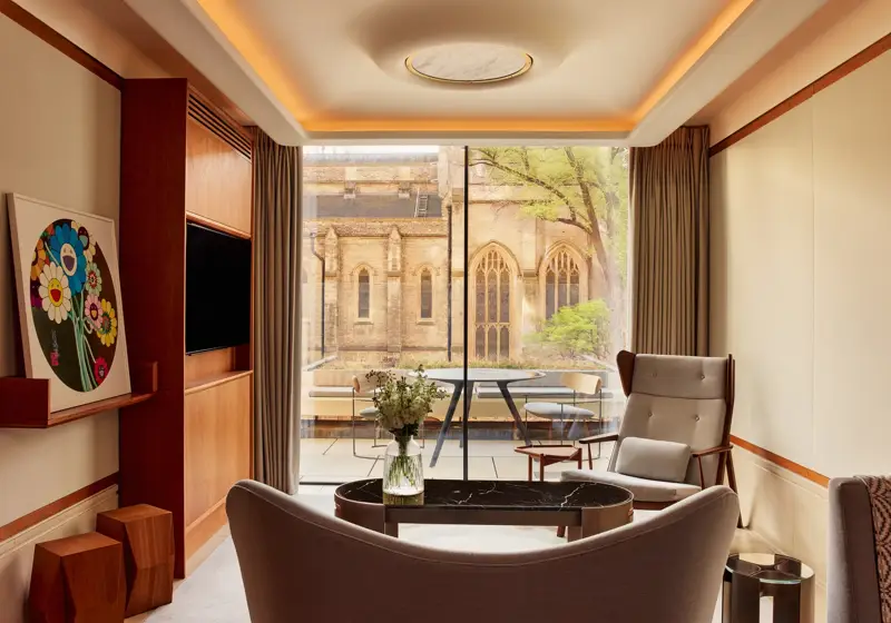 Modern living area with armchairs, artwork, and terrace view of historic church windows.