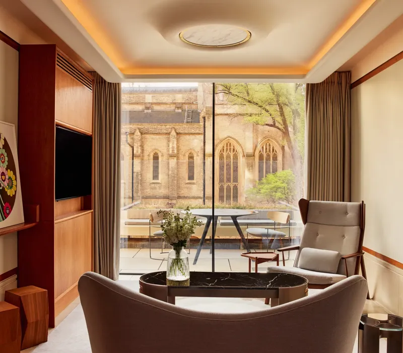 Modern living area with armchairs, artwork, and terrace view of historic church windows.