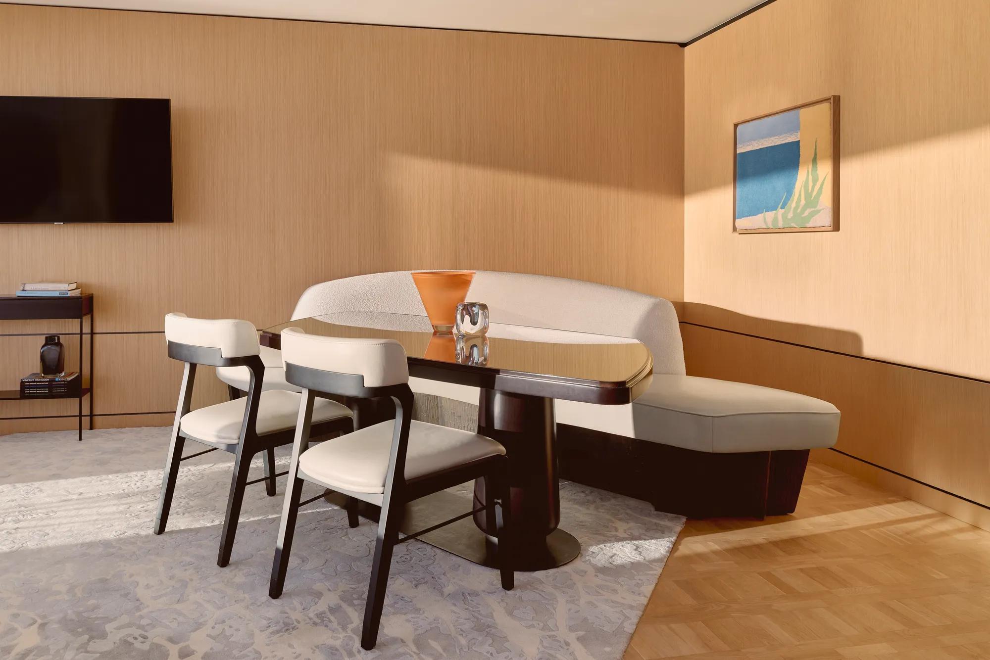 Coin repas élégant avec banquette courbée, chaises modernes et table en bois raffinée, décoré de vases sculpturaux.