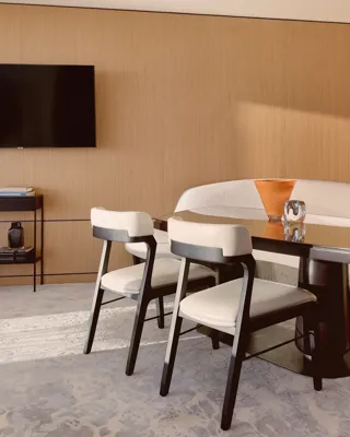 Coin repas élégant avec banquette courbée, chaises modernes et table en bois raffinée, décoré de vases sculpturaux.