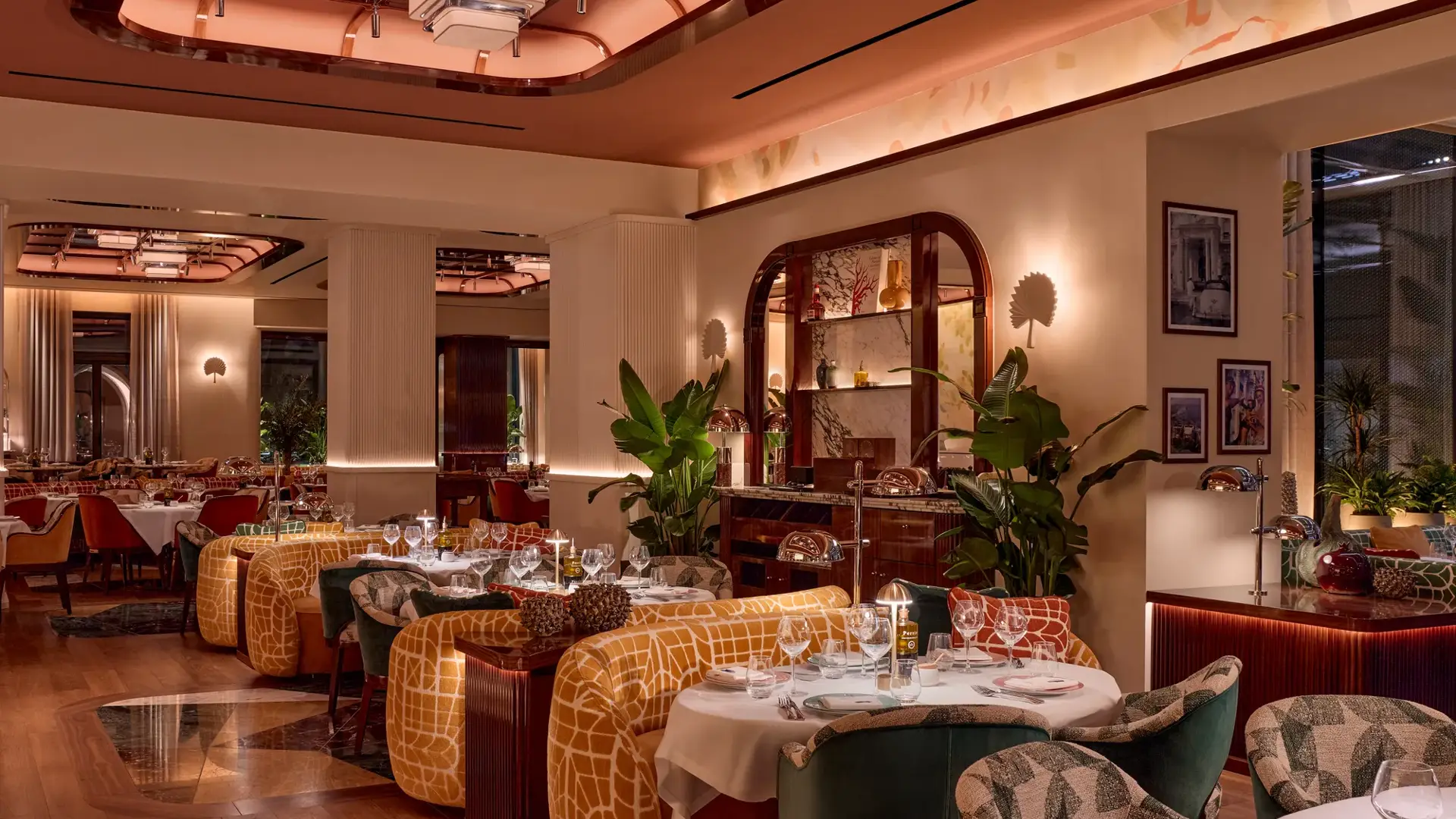 Elegant restaurant interior with patterned chairs, yellow banquettes, and warm ambient lighting.