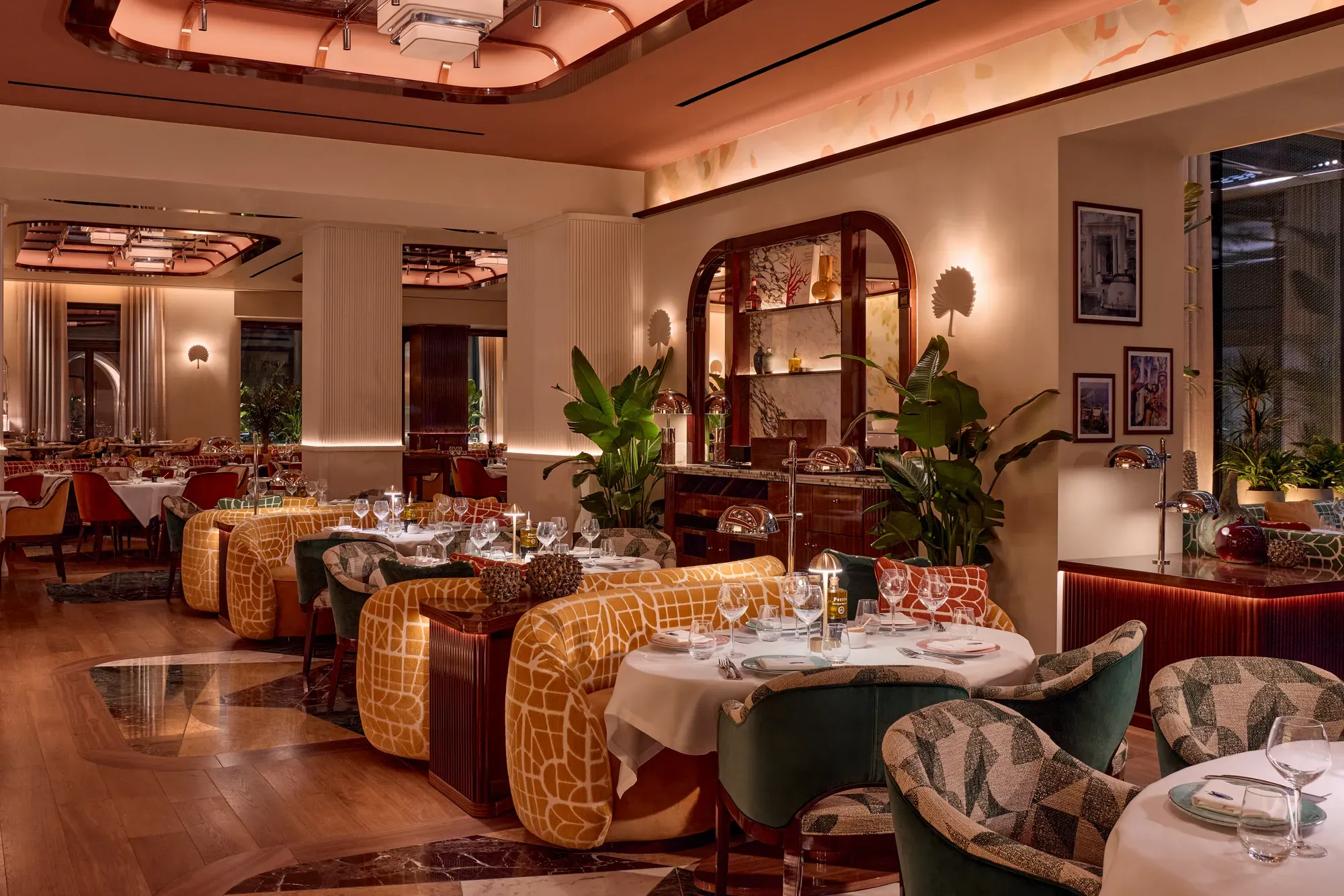Elegant restaurant interior with patterned chairs, yellow banquettes, and warm ambient lighting.
