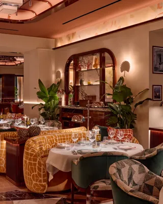 Elegant restaurant interior with patterned chairs, yellow banquettes, and warm ambient lighting.