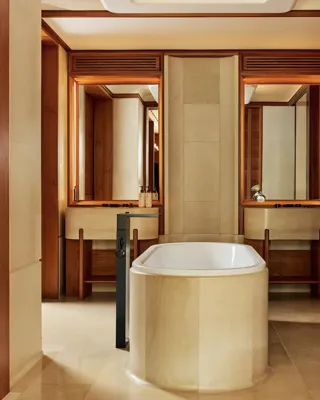 Bathroom with freestanding stone bathtub, twin vanities, and warm wood paneling.