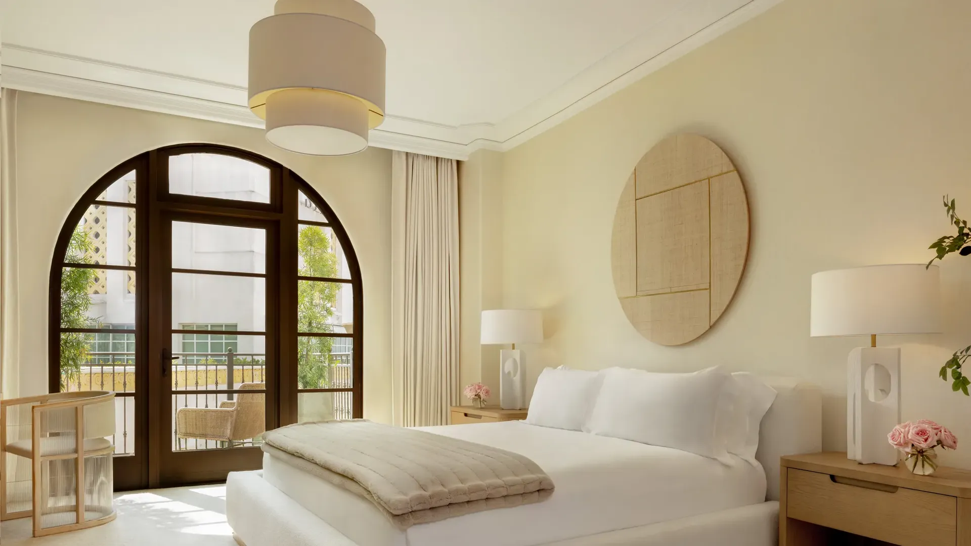 Elegant dining and living space in the Three-Bedroom Residence Wilshire, with a modern chandelier, plush seating, and panoramic city views.