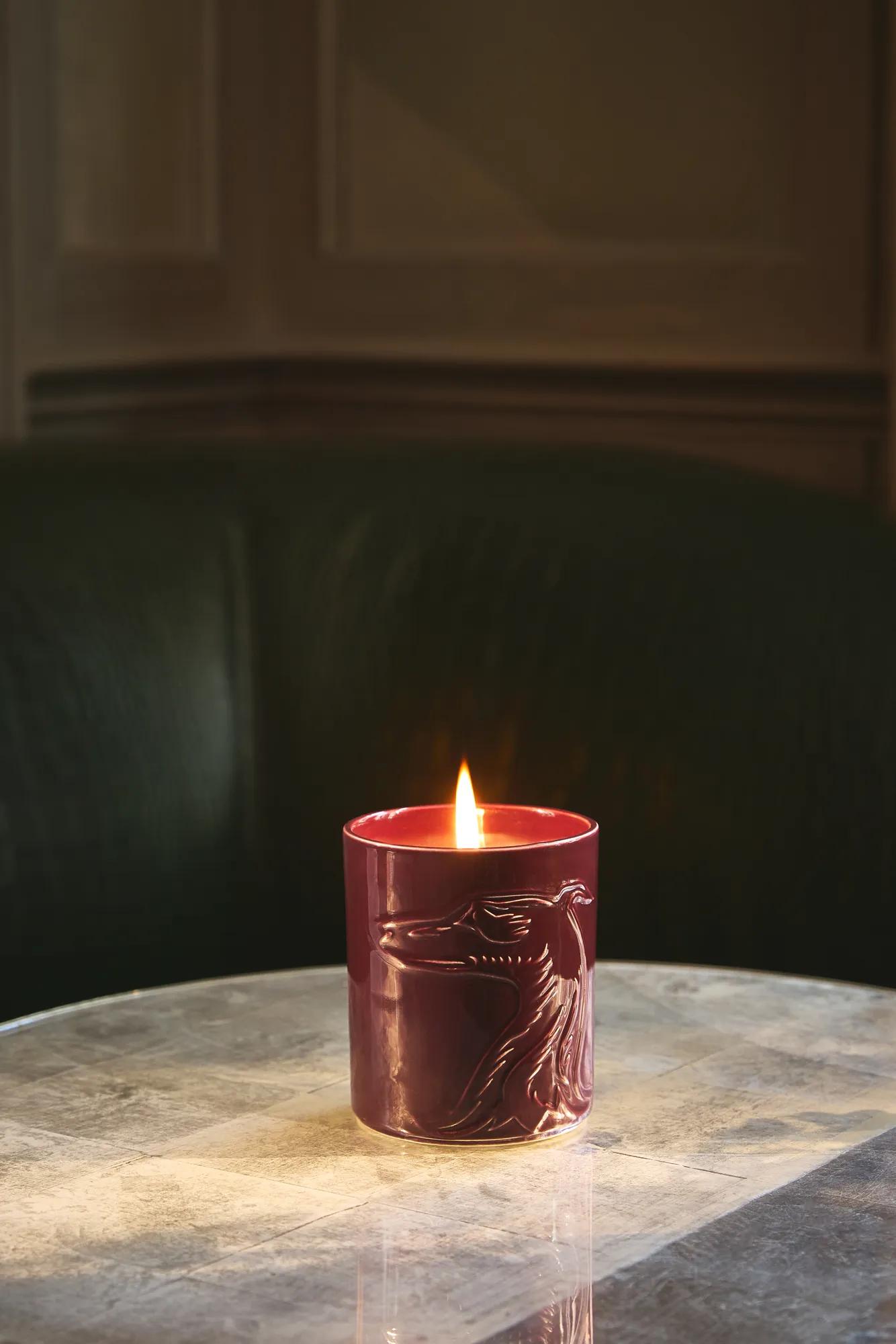 Lit burgundy candle on a marble table.