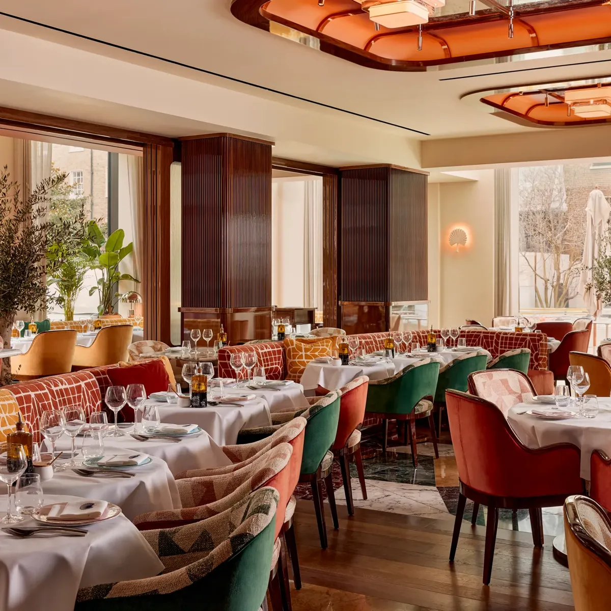 Elegant restaurant with plush velvet chairs, white tablecloths, and art deco ceiling lights.