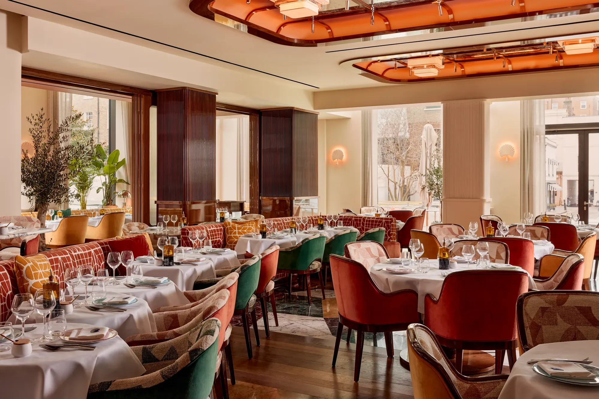 Elegant restaurant with plush velvet chairs, white tablecloths, and art deco ceiling lights.