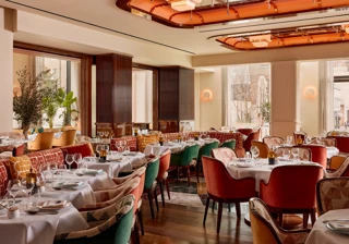 Elegant restaurant with plush velvet chairs, white tablecloths, and art deco ceiling lights.